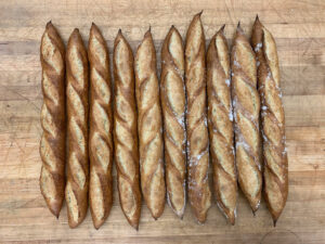 baguettes lined up on a wooden countertop